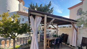 A covered outdoor patio with a pool, wooden deck, and seating area. - Charming Two-Story Villa with Private Pool and Garden in Miami Platja, Close to Catalan Coast (Miami Playa)