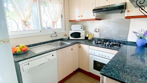 A compact kitchen with a dishwasher, a microwave, a stove, and a sink. - Charming Two-Story Villa with Private Pool and Garden in Miami Platja, Close to Catalan Coast (Miami Playa)