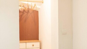 A room with a wooden wardrobe, a hanging clothes rack, and a small white dresser. - Charming Two-Story Villa with Private Pool and Garden in Miami Platja, Close to Catalan Coast (Miami Playa)