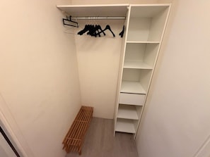 Un armario de acceso directo con un banco de madera, un perchero con ganchos y varias estanterías.
