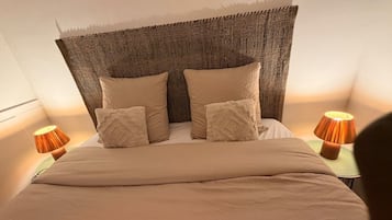 Ein Bett mit strukturierter Kopfteil, zwei Nachttischlampen und einem Bettgestell in neutralen Tönen.