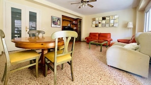 A living room with a dining table, chairs, a sofa, a coffee table, and a ceiling fan. - Spacious Apartment 300m from Salou Beach with A/C and Terrace (Salou)