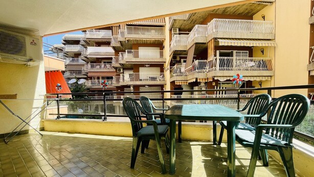A balcony with a table and chairs, overlooking a multi-story building with balconies. - Spacious Apartment 300m from Salou Beach with A/C and Terrace (Salou)