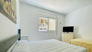 A bedroom with a bed, a dresser, a television, and a window with a view of a balcony. - Spacious Apartment 300m from Salou Beach with A/C and Terrace (Salou)