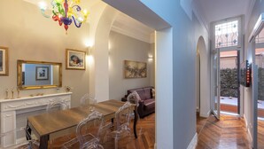 A dining area with a wooden table, clear glass chairs, a fireplace, and a chandelier. - Rental in Rome Gregoriana Apartment (Rome)