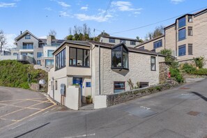 A modern two-story building with a stone facade, large windows, and a blue door.