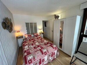 A bedroom with a large bed, a wardrobe, a chair, and a window. - Renovated apartment in Méaudre, 4 pers, terrace, near center (Méaudre)