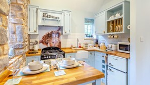 A kitchen with a stone wall, a stove, a sink, and a microwave. - 1 Bed in Drumnadrochit (oc-t32404) (Drumnadrochit)