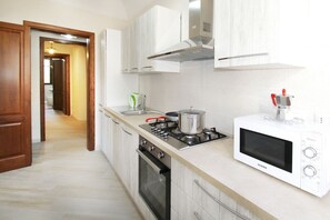 Eine moderne Küche mit Gasherd, Backofen, Mikrowelle und weißen Schränken.