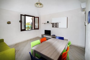 Un espacio habitable compacto con comedor, una kitchenette pequeña y un ventanal con vistas.