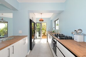 A modern kitchen with a wooden countertop, stainless steel appliances, and a view to the outdoors. - Spacious Family Camps Bay Escape |  Spectacular Views | Pool, Garden (Cape Town)