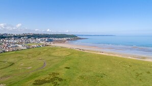 Une ville côtière dotée d’une plage, de champs verdoyants et d’immeubles d’habitation.