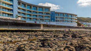 Un hôtel à plusieurs étages doté de balcons, situé sur une côte rocheuse, avec un ciel dégagé.