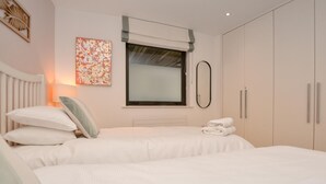 Une chambre avec deux lits, une fenêtre donnant sur un paysage agréable, un radiateur et un porte-serviettes.
