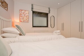 Ein Schlafzimmer mit zwei Betten, einem Fenster mit Aussicht, einem Heizkörper und einem Handtuchhalter.