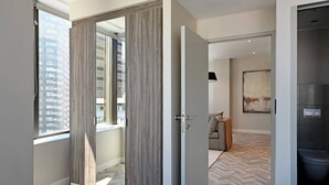 Una habitación de hotel moderna con un ventanal grande, piso con patrón de espiga y diseño minimalista.