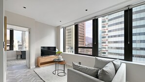 Una sala de estar moderna con un sofá, televisor y una mesita con una planta.