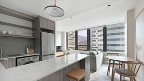 Una cocina moderna con una isla grande, electrodomésticos integrados y un comedor con vistas a la ciudad.