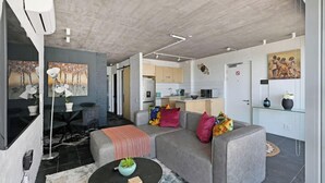 Un soggiorno moderno con un divano grigio, un tavolino rotondo e un'area pranzo con un piccolo tavolo e sedie.