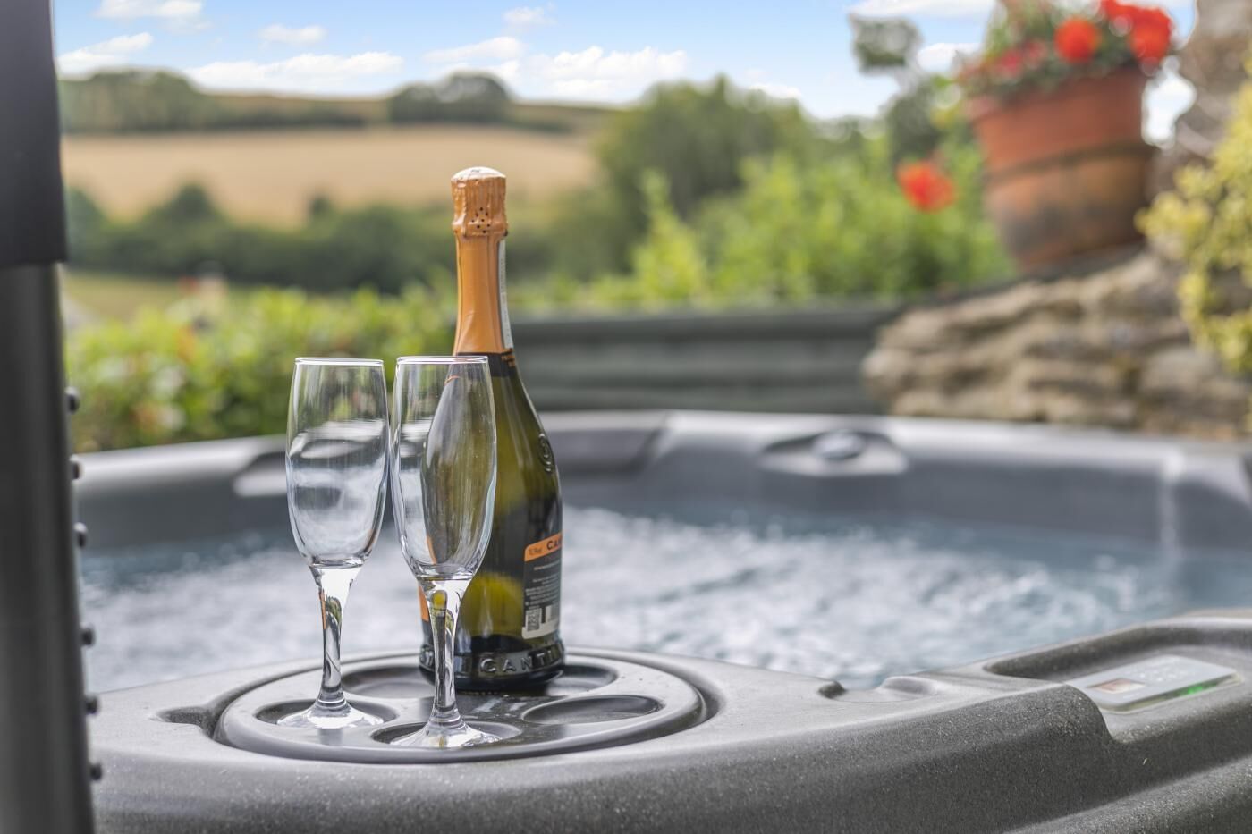 A hot tub with two glasses and a bottle of champagne.