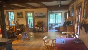 A cozy room with wooden floors, a dining table with chairs, a sewing machine, and a rocking chair.
