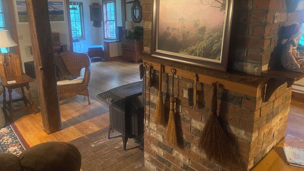 A rustic room with a fireplace, wooden furniture, and a large framed landscape painting.
