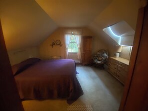 A bedroom with a bed, a dresser, a chair, and a window with curtains.