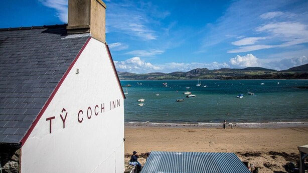 Un bâtiment situé sur la côte, appelé « TY COCH INN », qui offre une vue sur la mer et les bateaux.