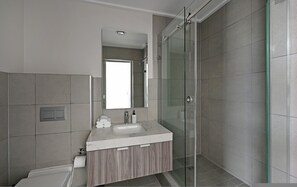 Ein modernes Badezimmer mit Duschkabine aus Glas, einem Waschbecken mit Marmorplatte und einem Holzwaschtisch.