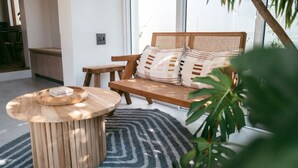 Een moderne woonkamer met een houten bankje, een ronde salontafel en een groot raam.