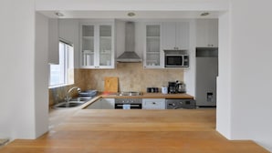 Una cocina moderna con armarios blancos, electrodomésticos de acero inoxidable y encimera de madera.