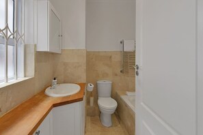 Un bagno con lavandino, WC e vasca bianca.
