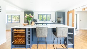 Una cocina moderna con una isla central, taburetes de bar y un refrigerador para vino empotrado.