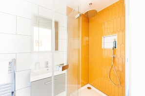 Un bagno moderno con box doccia in vetro, lavandino bianco e specchio.