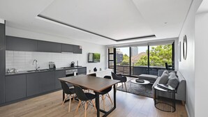 Et moderne køkken med spiseplads, sofa og TV.