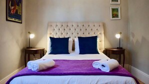 A neatly made bed with a tufted headboard, two pillows, and a purple blanket. - Spacious 3 Bedroom Home | Green Point (Cape Town)