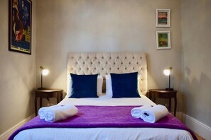 A neatly made bed with a tufted headboard, two pillows, and a purple blanket.
