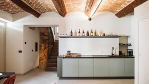 A modern kitchen with a stone ceiling, a built-in wine rack, and a staircase leading to another level. - Vicolo al Castello - Langhe e Monferrato Suites (Costigliole d'Asti)