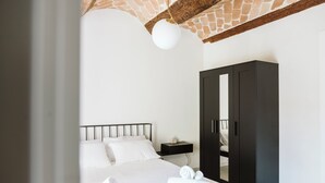 A bedroom with a bed, a wardrobe, a nightstand, and a hanging light fixture. - Vicolo al Castello - Langhe e Monferrato Suites (Costigliole d'Asti)
