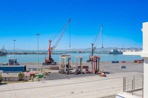 A port with cranes and shipping containers, a large ship docked, and a clear blue sky. - Spacious 2Bed Harbor Haven | V&A Waterfront Canals (Cape Town)