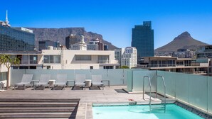 A rooftop pool area with lounge chairs and a view of city buildings and a mountain. - Spacious 2Bed Harbor Haven | V&A Waterfront Canals (Cape Town)