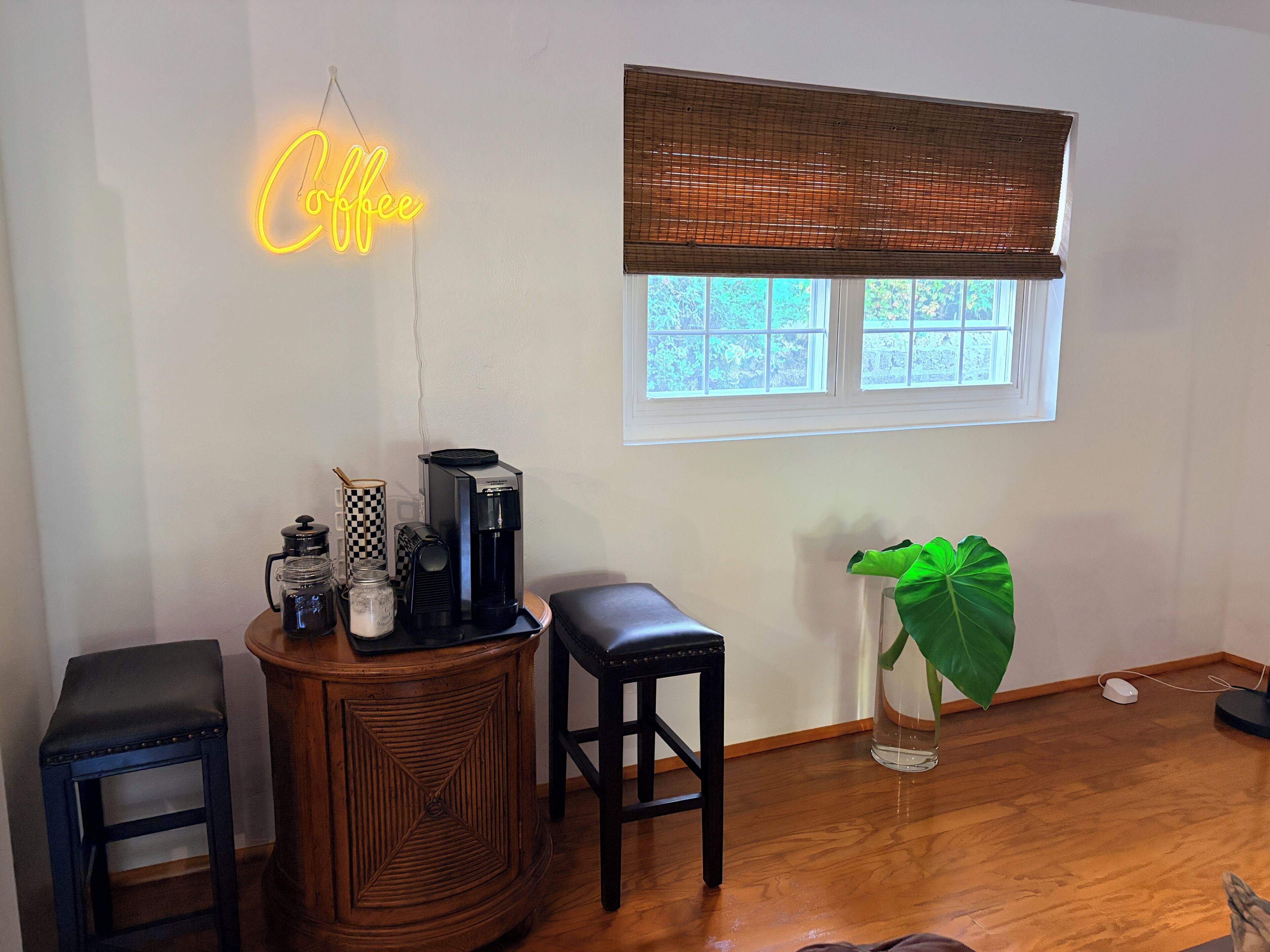 Quarto com um espaço para café, uma janela com vista, uma planta e uma caneca xadrez.
