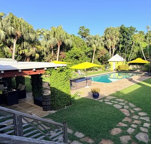 A backyard with a swimming pool, yellow umbrellas, and a small gazebo.