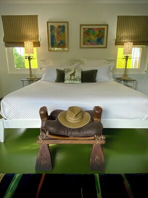A bed with a white quilt, two pillows, two wall-mounted lamps, and two framed artworks.