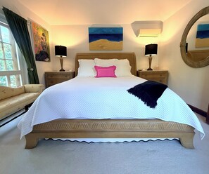 Une chambre à coucher avec un lit, des tables de chevet, une lampe, un miroir et des œuvres d’art accrochées aux murs.