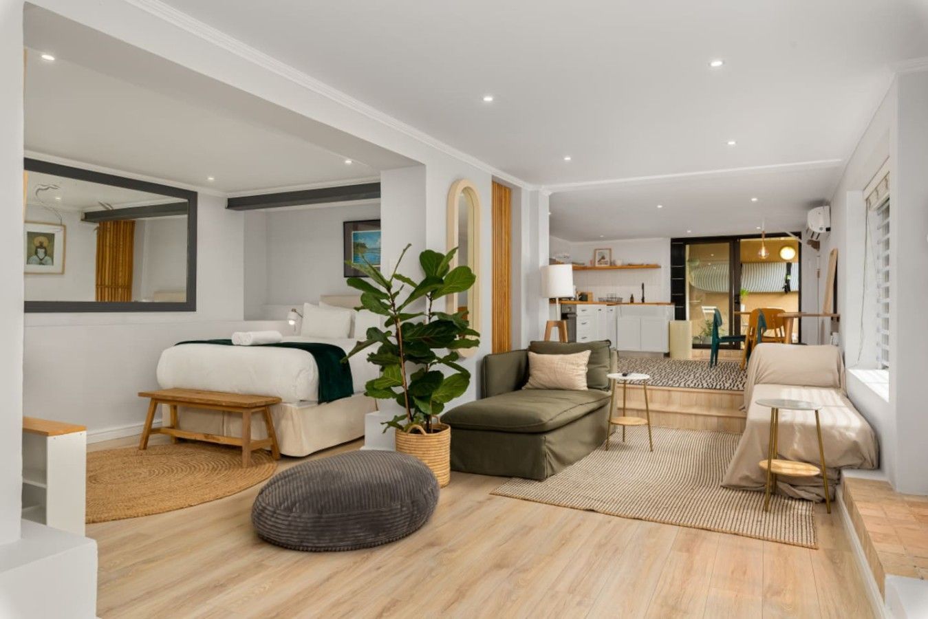 Een moderne hotelkamer met een bed, zithoek en uitzicht op de keuken.