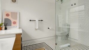 Un baño moderno con cabina de ducha de vidrio, inodoro y zona de lavamanos.
