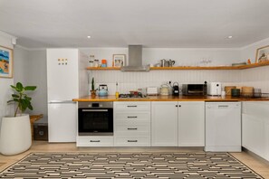 Una cocina moderna con armarios blancos, horno integrado, microondas y lavavajillas.