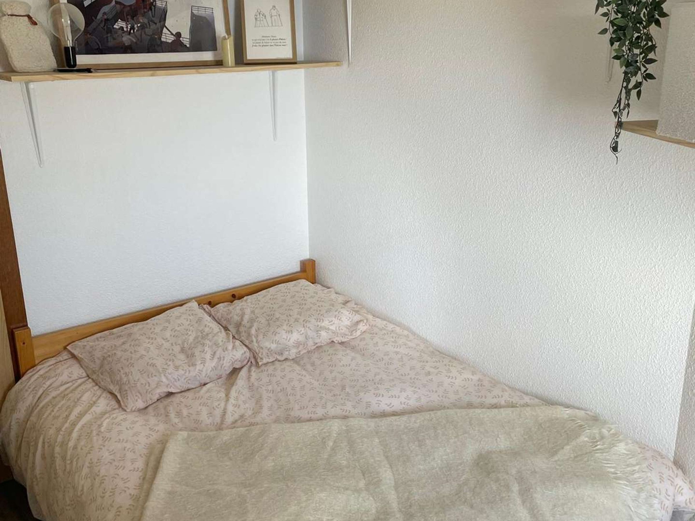 Una cama individual con estructura de madera y colcha estampada.