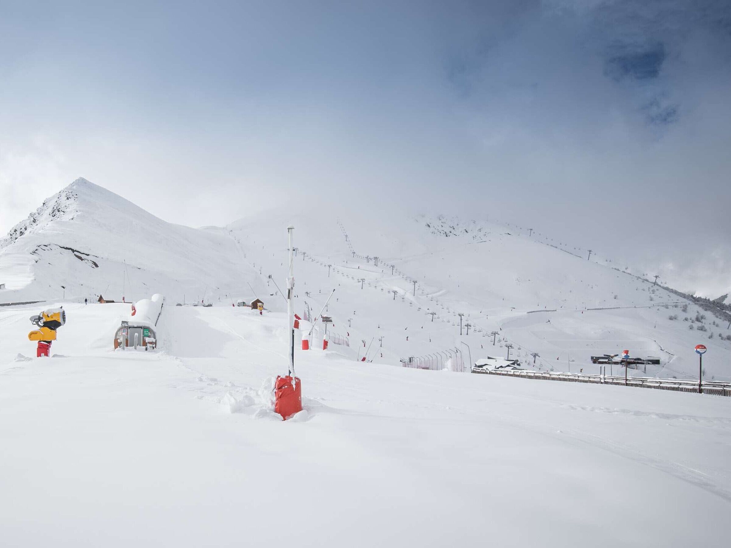 A snow-covered mountain with ski lifts and a small building.